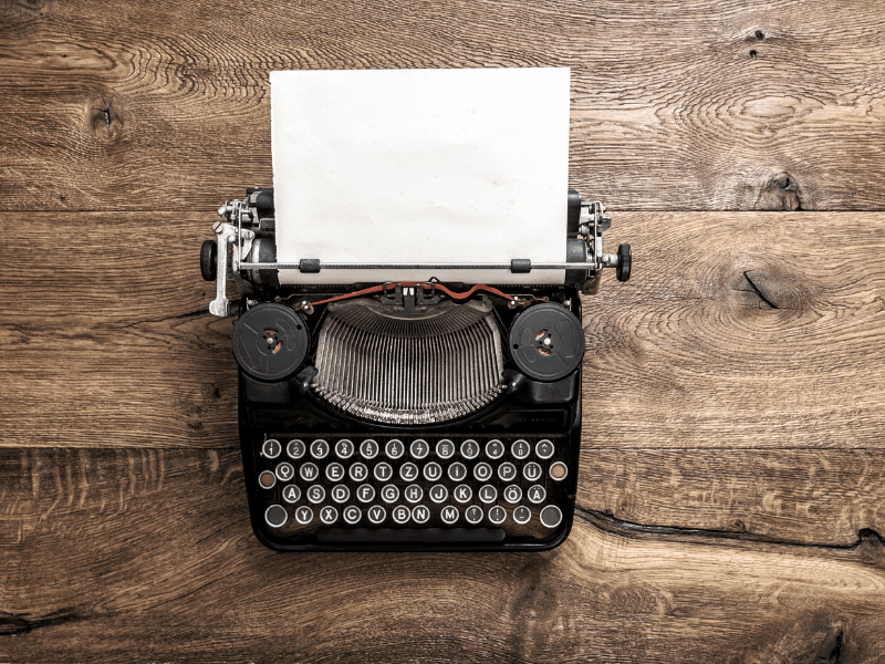 A vintage typewriter with a blank sheet of paper on a wooden desk, symbolizing timeless creativity and the power of starting to write.