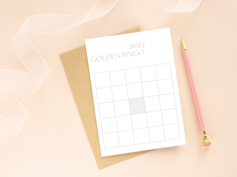 A minimalist Golden Era Bingo card template on a beige notebook with a pink pen, ready for goal-setting and planning.