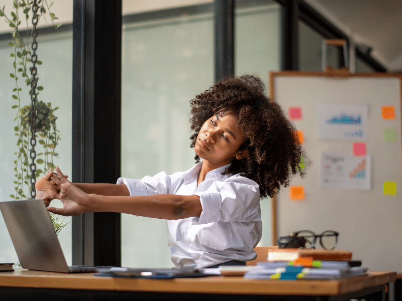 Person stretching at their desk in a bright home office, promoting mindfulness and healthy breaks during remote work