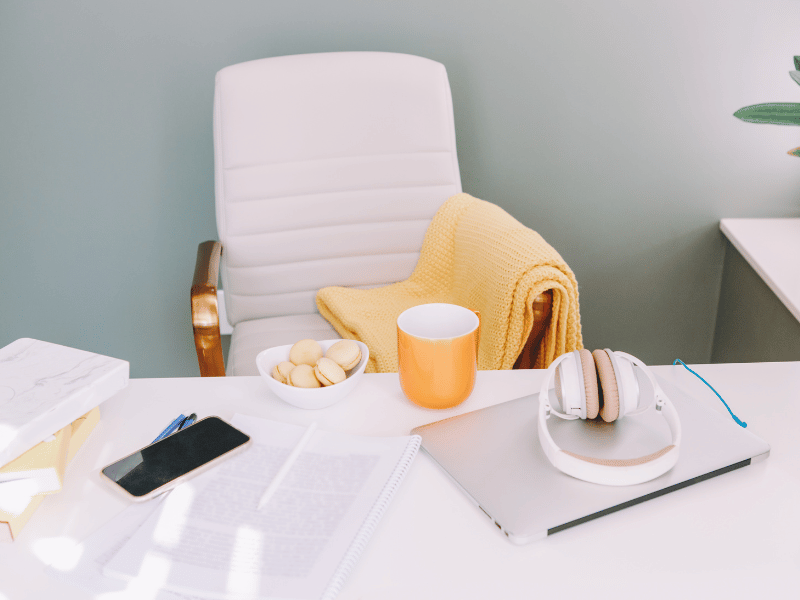 Minimalist workspace with a white ergonomic chair, a table holding a coffee mug, papers, and a phone, exemplifying a clean and functional home office