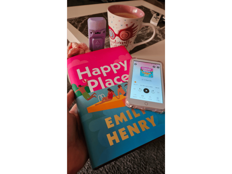 Happy Place by Emily Henry with a cup of tea and audiobook playing on an Oilsky mp3 player.