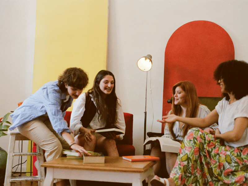 Small group of people sitting together reading and talking, representing creative community, shared accountability, and support among writers.